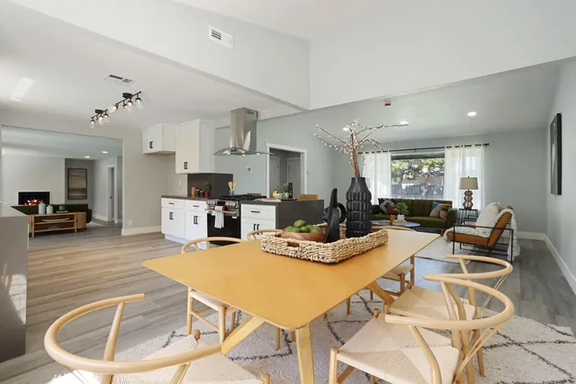 a kitchen with stainless steel appliances kitchen island granite countertop a refrigerator a stove a sink dishwasher and white cabinets with wooden floor