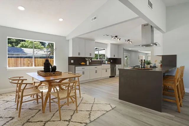 a large white kitchen with cabinets a sink a window and stainless steel appliances