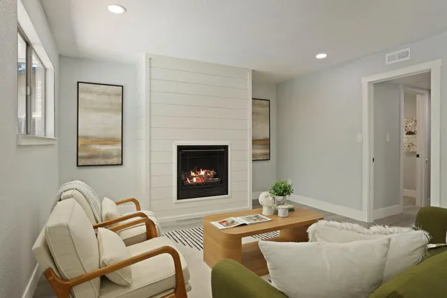a view of a hallway to a livingroom with wooden floor and furniture
