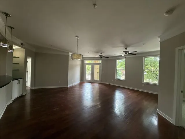 a view of empty room with wooden floor and fan