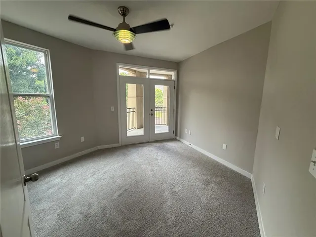 an empty room with a window and chandelier fan