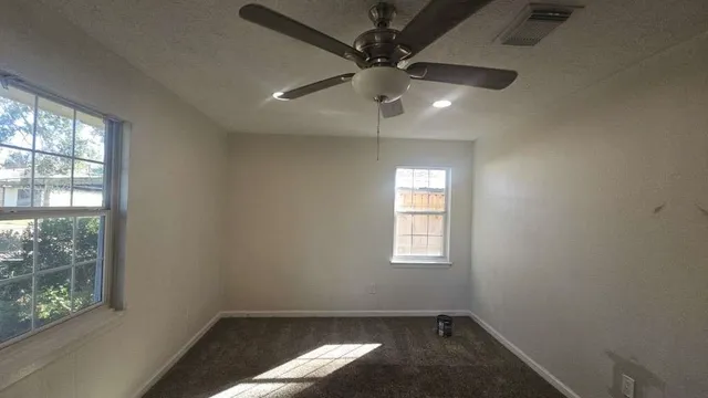 an empty room with a window and a fan