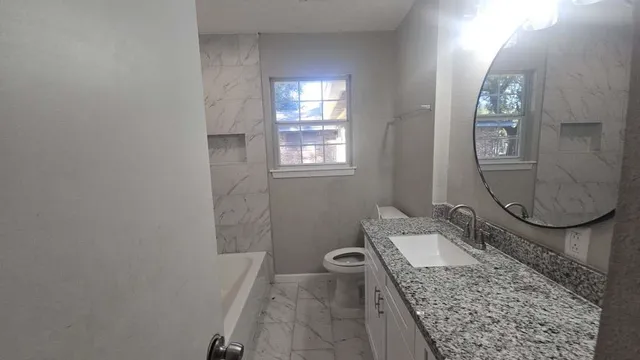 a bathroom with a granite countertop sink a mirror and vanity