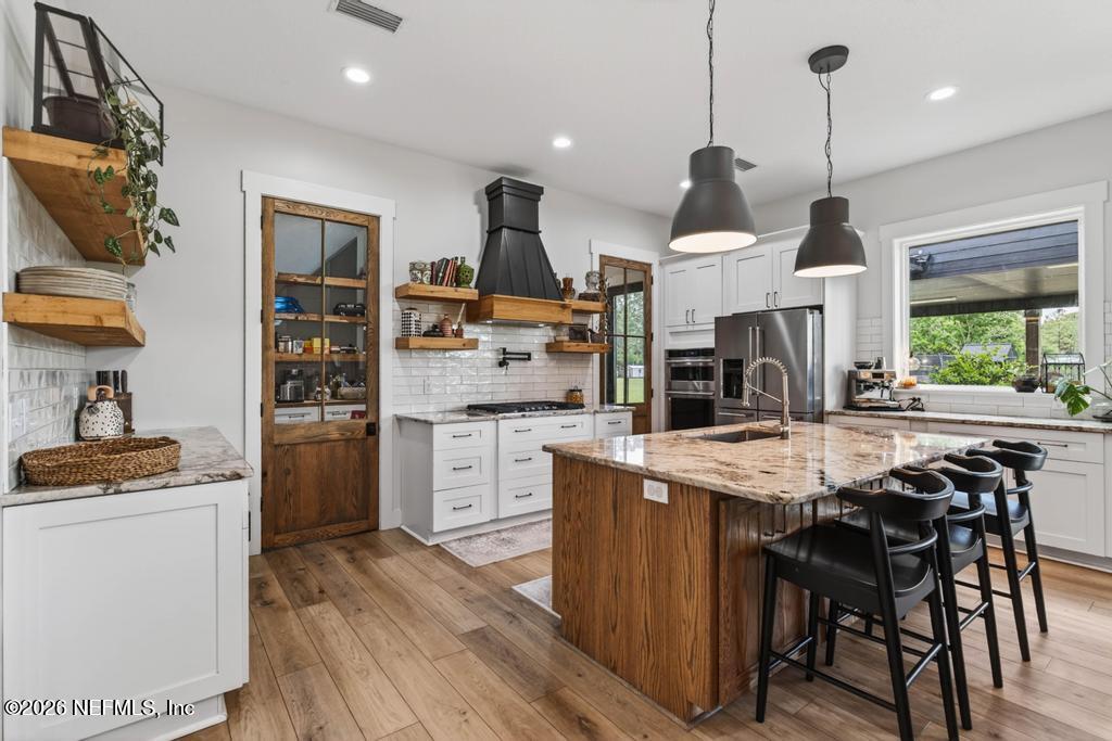 2955 Carroll Corner Road Hilliard, FL 32046 - Photo 31 of 106 a kitchen with stainless steel appliances kitchen island granite countertop a stove a sink dishwasher and a refrigerator with wooden floor