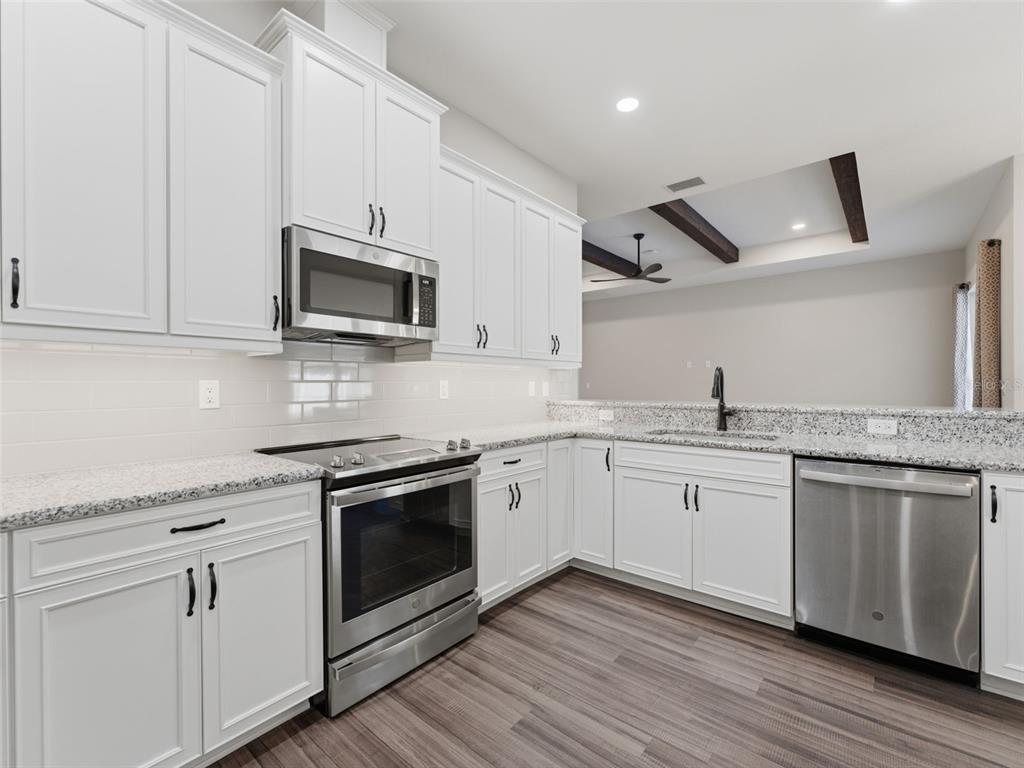 4025 Spring Park Way Brooksville, FL 34604 - Photo 13 of 97 a kitchen with granite countertop cabinets stainless steel appliances and wooden floor