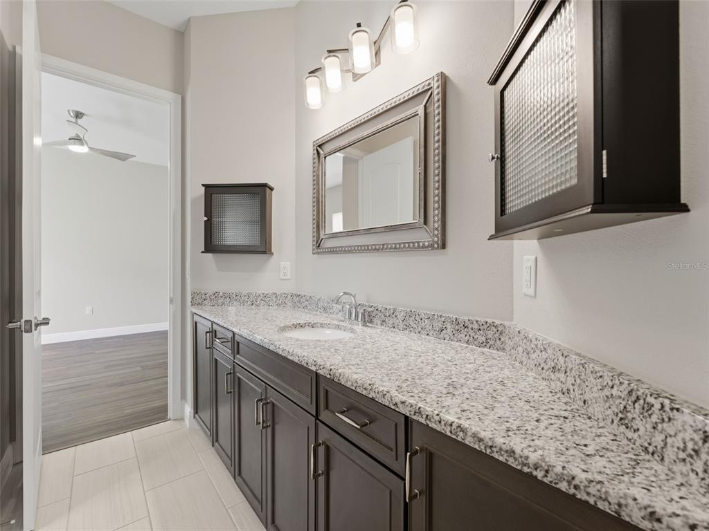 4025 Spring Park Way Brooksville, FL 34604 - Photo 58 of 97 a en suite bathroom with a granite countertop sink and a mirror