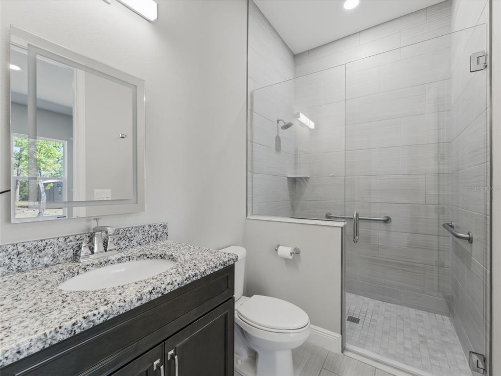 4025 Spring Park Way Brooksville, FL 34604 - Photo 69 of 97 a bathroom with a granite countertop sink a toilet and shower