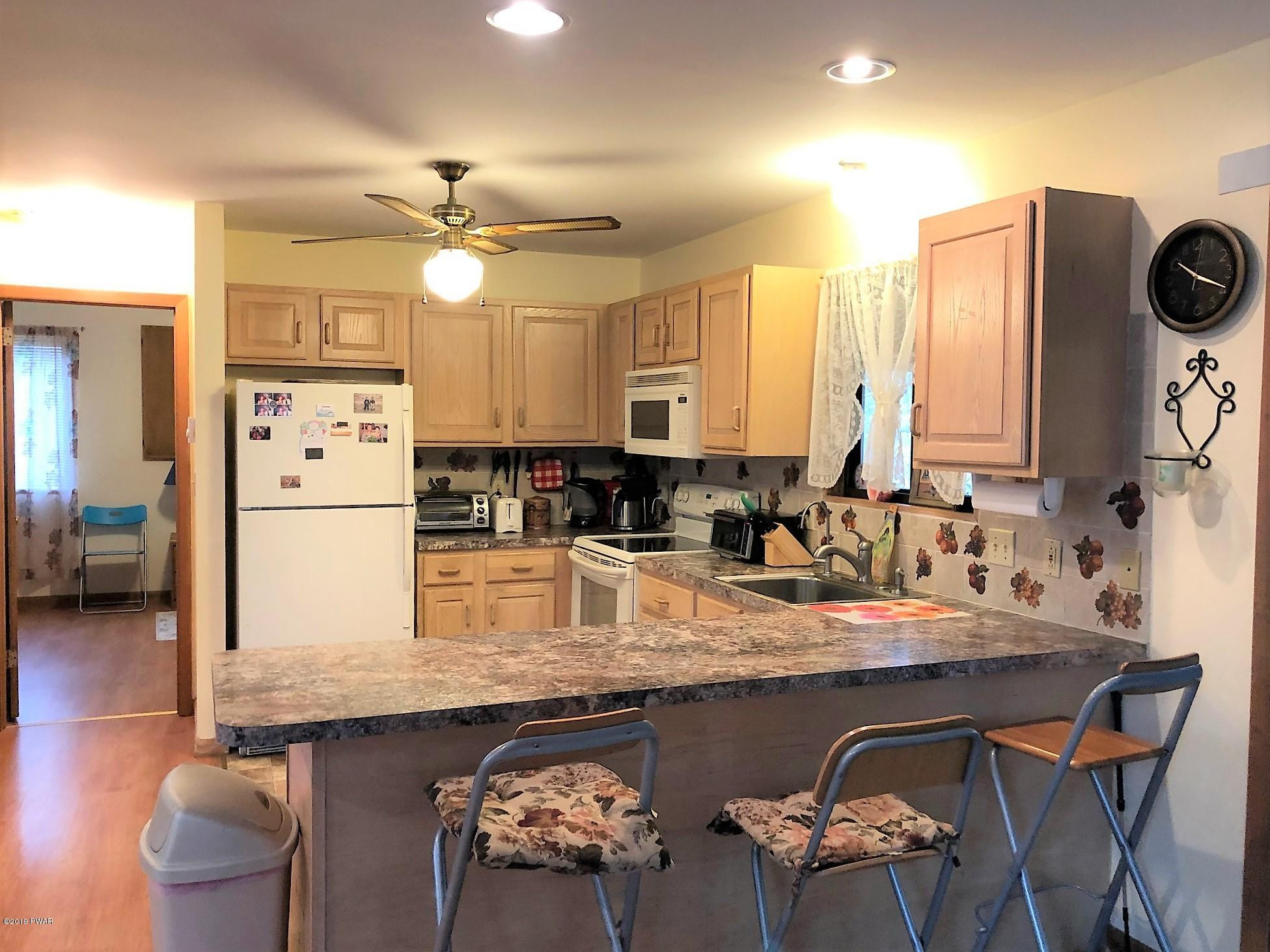 3039 Northgate Road Lake Ariel, PA 18436 - Photo 6 of 57 a kitchen with stainless steel appliances granite countertop a stove a refrigerator a sink a dining table and chairs with wooden floor