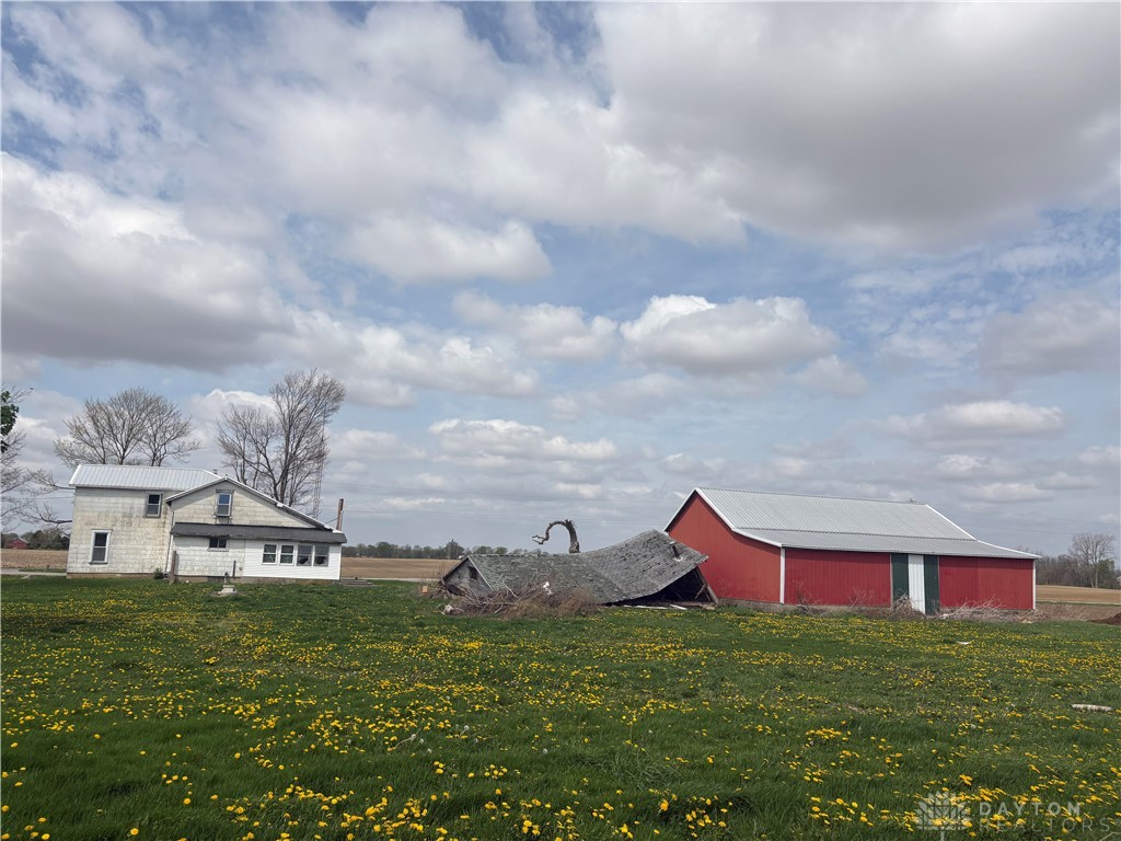 9006 Oakes Road Arcanum, OH 45304 - Photo 8 of 29 This pastoral landscape showcases a charming farmhouse nestled amongst vibrant greenery.