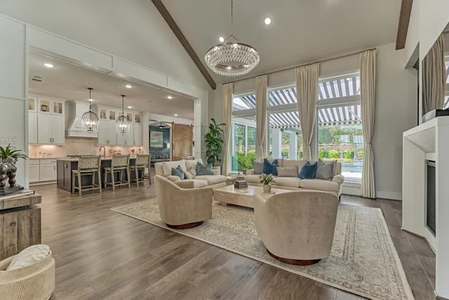 a living room with furniture a large window and wooden floor