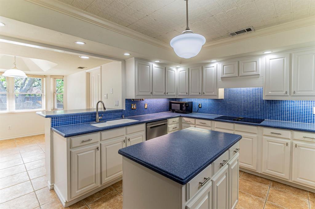 127 Nicklaus Nook Lancaster, TX 75146 - Photo 11 of 37 Kitchen with a peninsula, ornamental molding, pendant lighting, dark countertops, and a kitchen island
