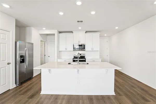 a large kitchen with stainless steel appliances granite countertop a white stove top oven a refrigerator a sink and a refrigerator