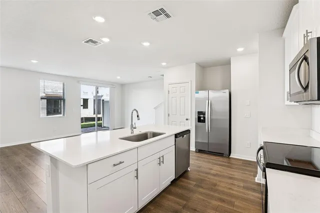 a kitchen with stainless steel appliances kitchen island a refrigerator sink and cabinets