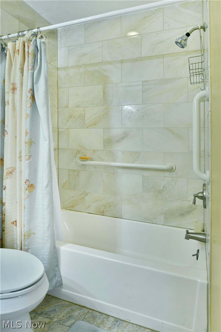 3287 Pheasant Run Road, Unit B Cortland, OH 44410 - Photo 39 of 45 White bathtub with a tile surround, stainless steel showerhead, and grab bars