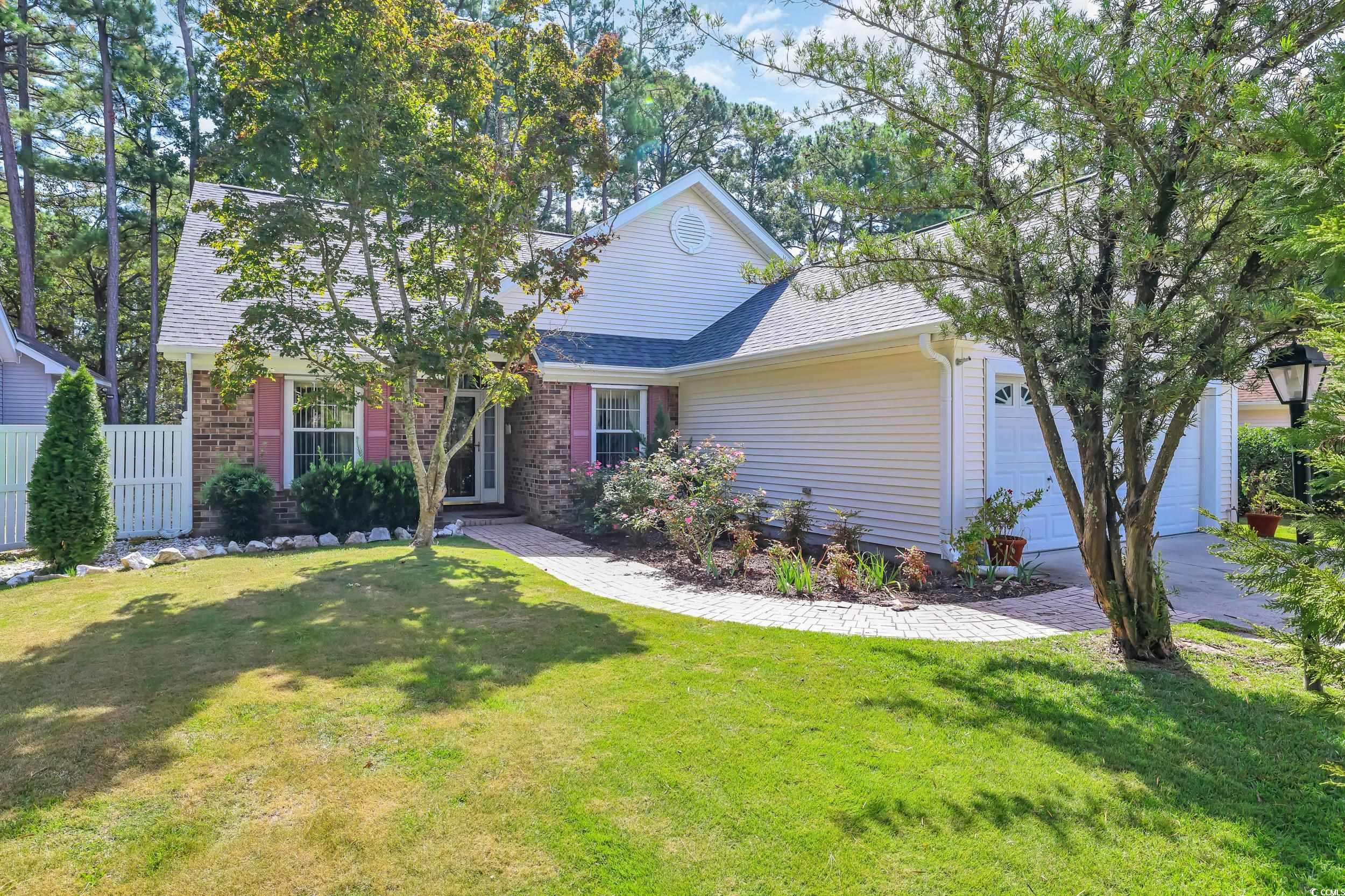 View of front of home with a garage, roof with shingles, and brick siding