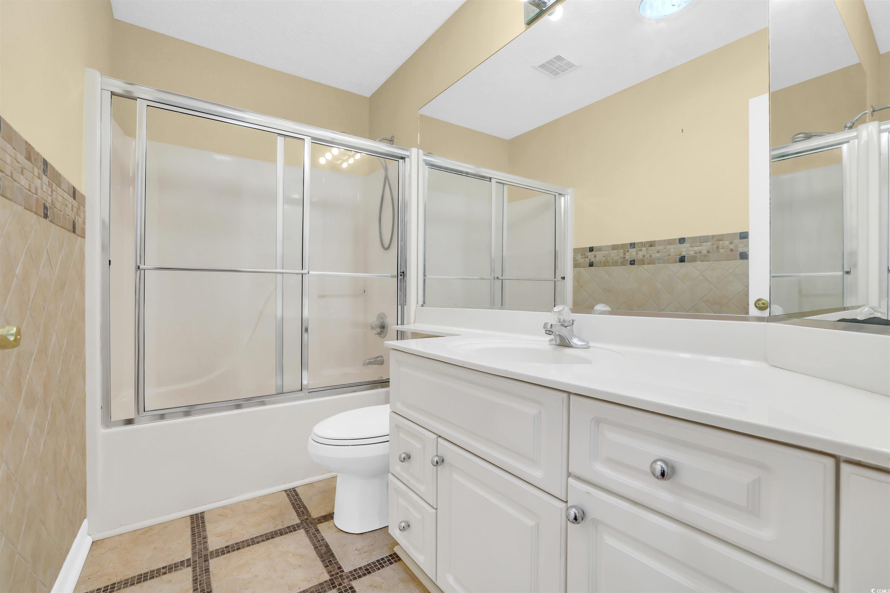 9350 Pinckney Lane Murrells Inlet, SC 29576 - Photo 12 of 40 Bathroom featuring inlaid floor details, shower / bath combination with glass door, vanity, and light tile patterned floors