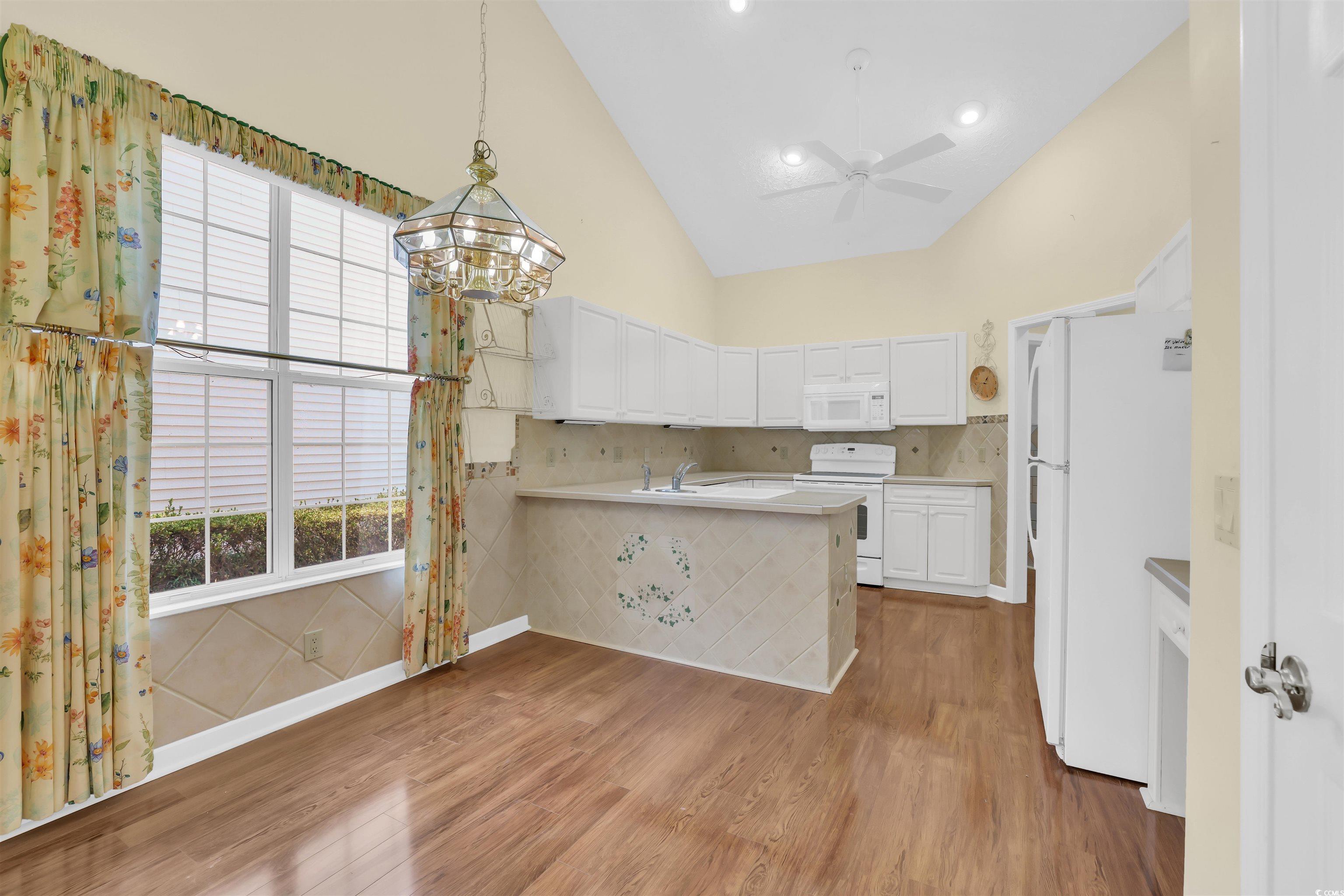 9350 Pinckney Lane Murrells Inlet, SC 29576 - Photo 29 of 40 Kitchen featuring high vaulted ceiling, white appliances, white cabinets, plenty of natural light, and hanging light fixtures
