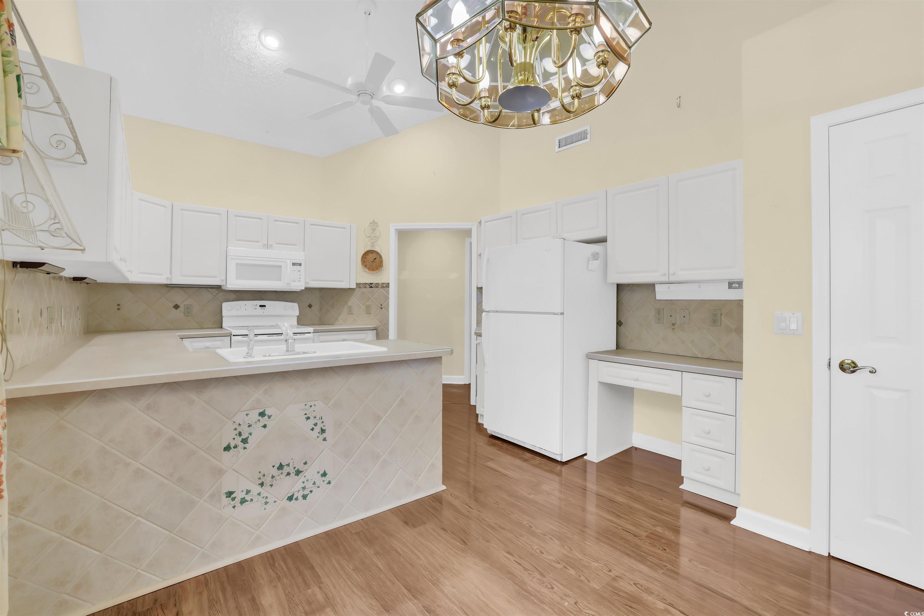 9350 Pinckney Lane Murrells Inlet, SC 29576 - Photo 30 of 40 Kitchen featuring tasteful backsplash, white appliances, light countertops, a peninsula, and white cabinetry