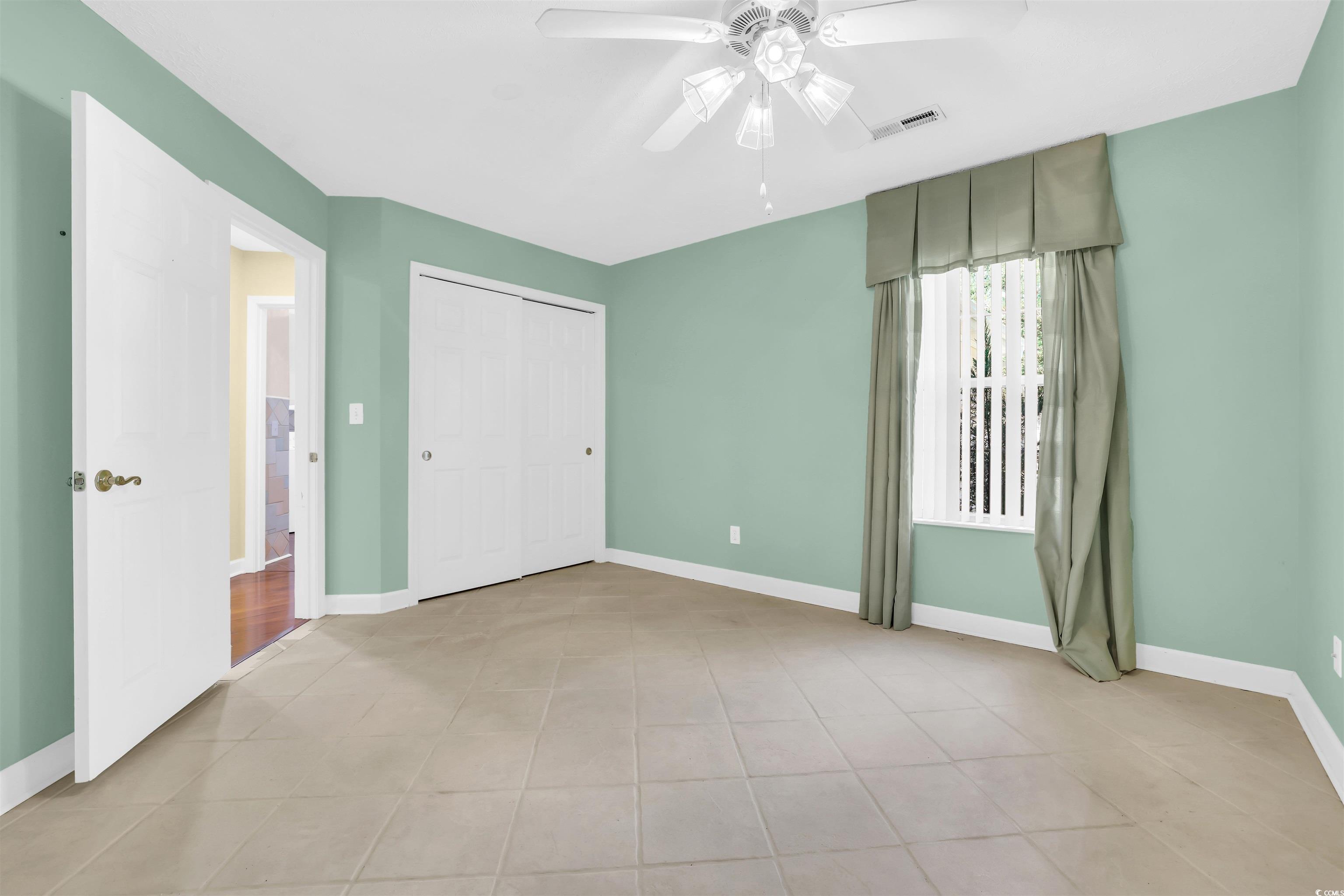 9350 Pinckney Lane Murrells Inlet, SC 29576 - Photo 10 of 40 Unfurnished bedroom featuring light tile patterned flooring, a ceiling fan, and a closet
