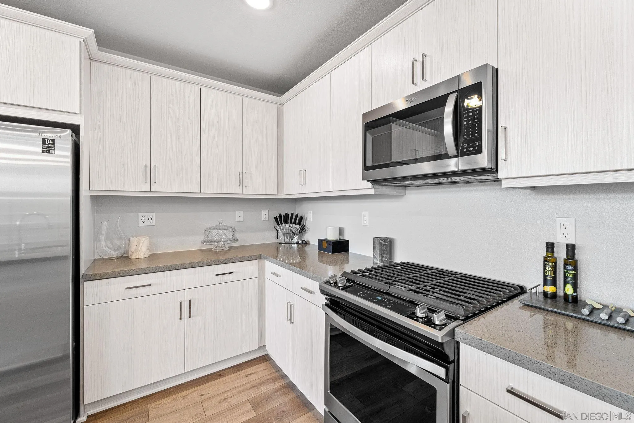 3002 Bravo Loop, Unit 4 Chula Vista, CA 91915 - Photo 15 of 38 a kitchen with stainless steel appliances granite countertop white cabinets a stove a microwave and a sink