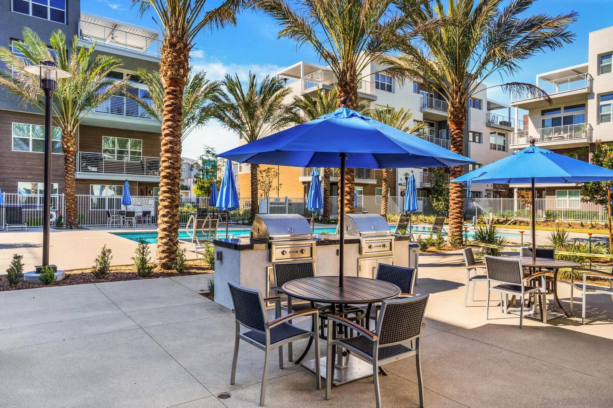 3002 Bravo Loop, Unit 4 Chula Vista, CA 91915 - Photo 37 of 38 a view of a patio with a dining table and chairs under an umbrella with a barbeque