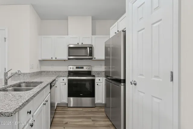 a kitchen with granite countertop a refrigerator stove and sink