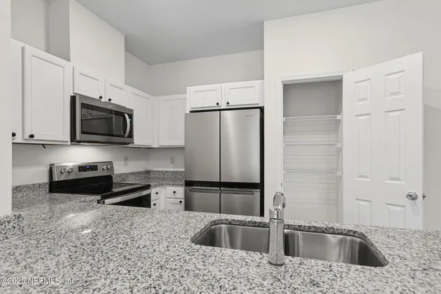 a kitchen with stainless steel appliances granite countertop a refrigerator a microwave a sink and cabinets