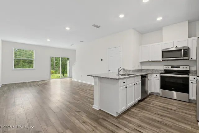 a kitchen with granite countertop a stove top oven and cabinets