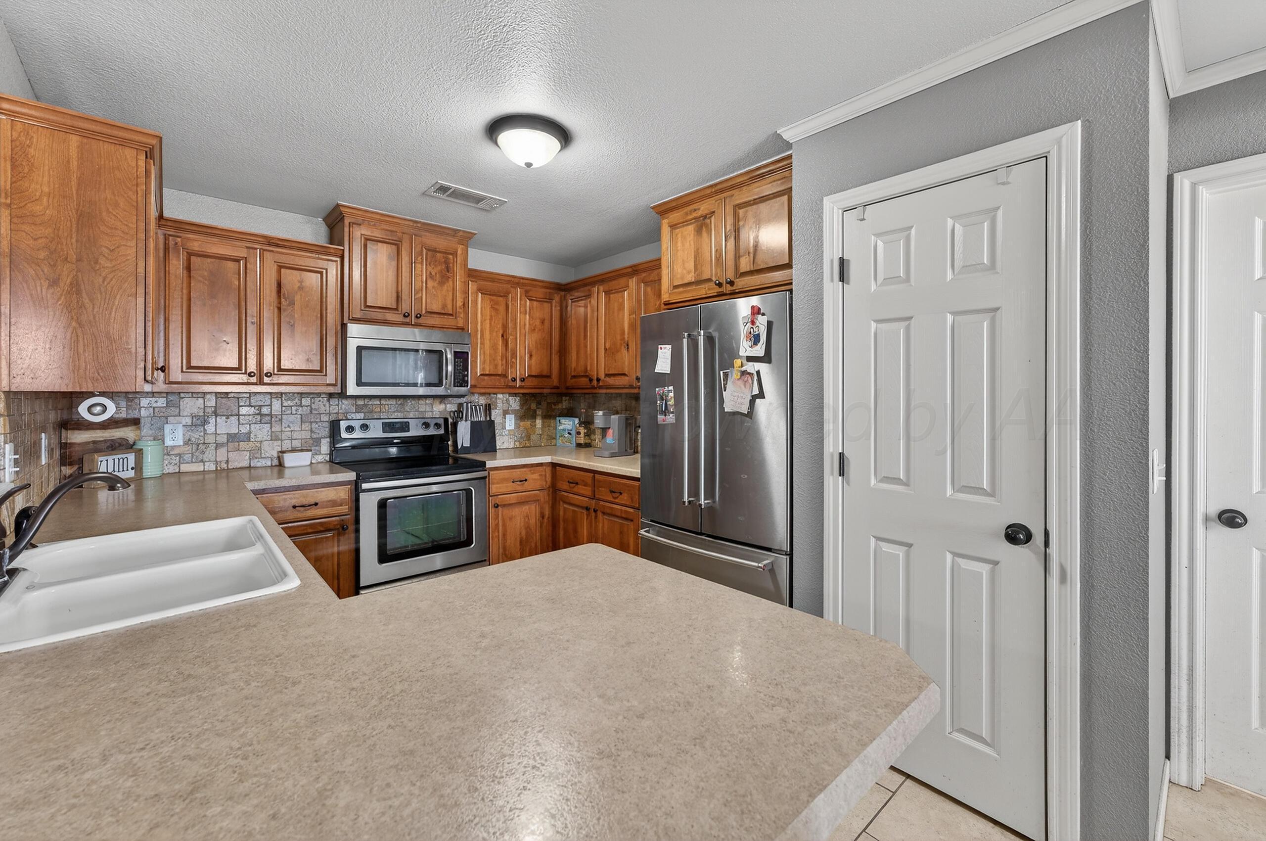 383 County Road 309 Panhandle, TX 79068 - Photo 7 of 35 a kitchen with granite countertop a refrigerator a sink a stove and cabinets