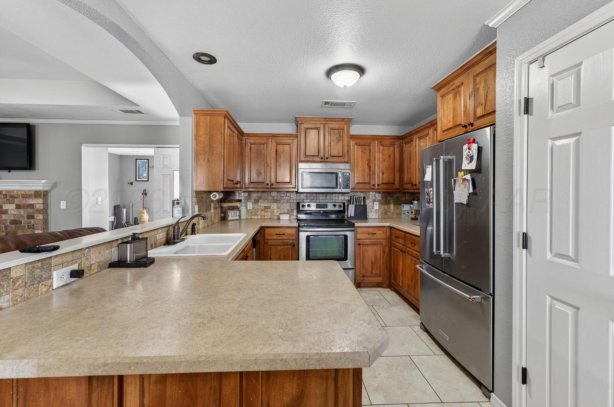 383 County Road 309 Panhandle, TX 79068 - Photo 8 of 35 a kitchen with stainless steel appliances granite countertop a refrigerator a stove and a sink with wooden floor