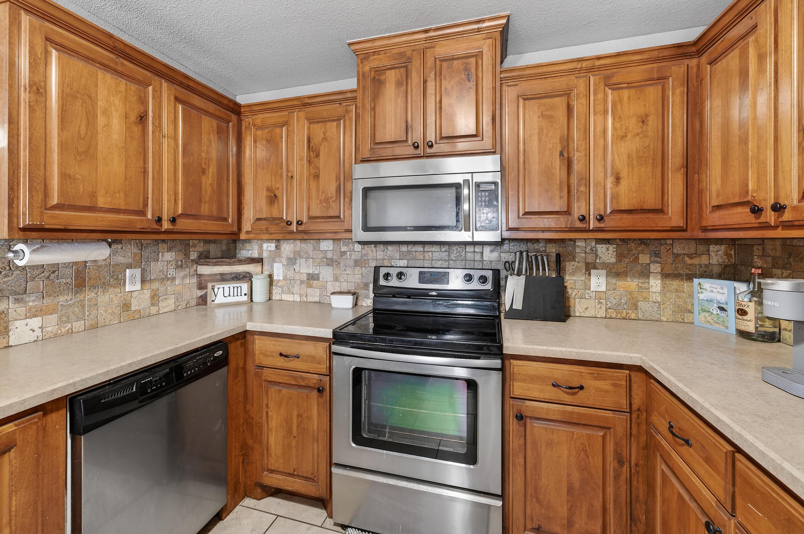 383 County Road 309 Panhandle, TX 79068 - Photo 9 of 35 a kitchen with granite countertop wooden cabinets and a stove top oven
