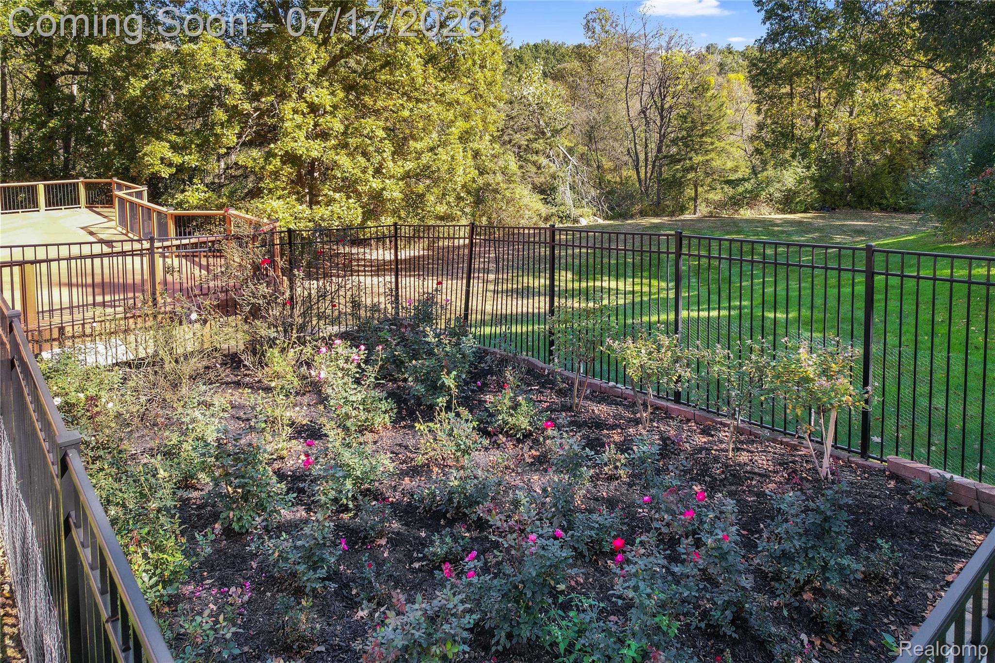 5685 Paint Valley Drive Rochester, MI 48306 - Photo 59 of 66 Expansive outdoor space featuring a multi-level deck with wood railing, a black wrought iron fence, and a landscaped garden bed with flowering shrubs