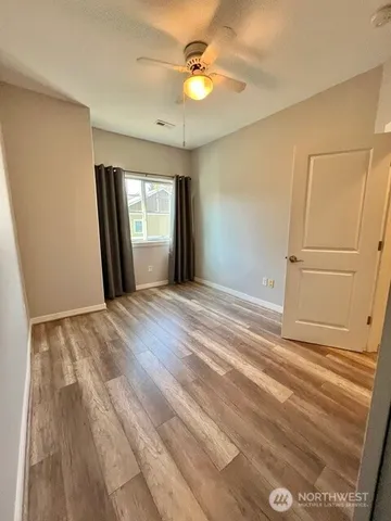 a view of an empty room with window and chandelier fan