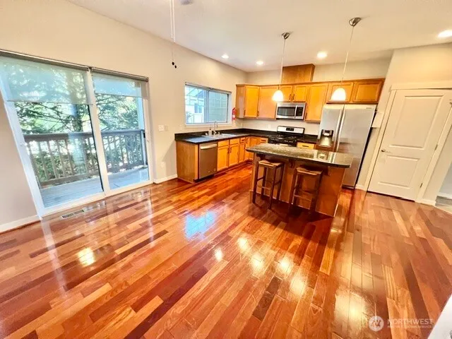 a kitchen with stainless steel appliances a refrigerator a stove top oven and a sink with wooden floor