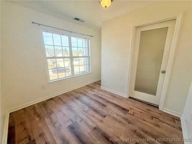 an empty room with wooden floor and windows