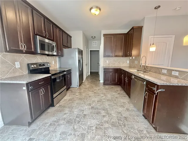a large kitchen with stainless steel appliances granite countertop a stove a sink dishwasher and a refrigerator