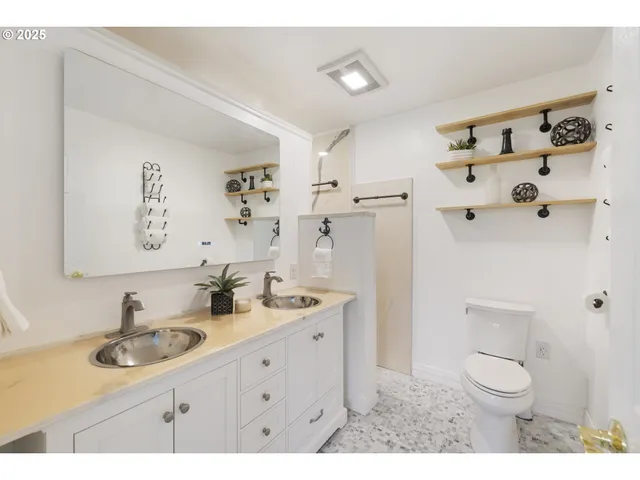 a bathroom with a sink toilet double vanity and shower