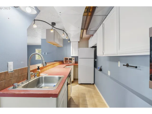 a kitchen with a sink a refrigerator and cabinets