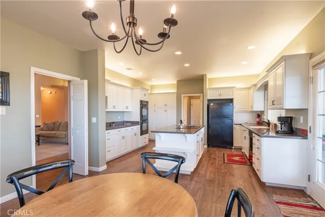 a dining room with wooden floor a chandelier a wooden table and chairs
