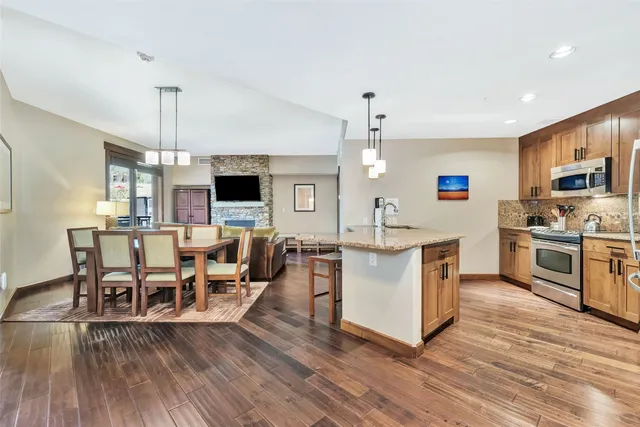 a living room with stainless steel appliances kitchen island furniture and a wooden floor
