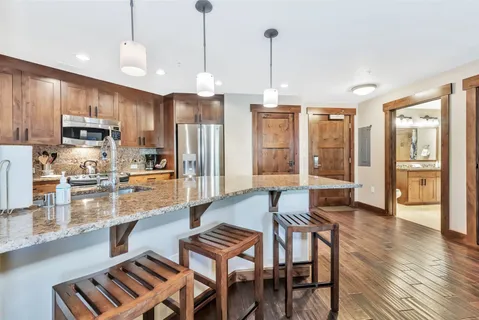 a kitchen with stainless steel appliances kitchen island granite countertop a refrigerator a stove a kitchen island with a dining table and chairs