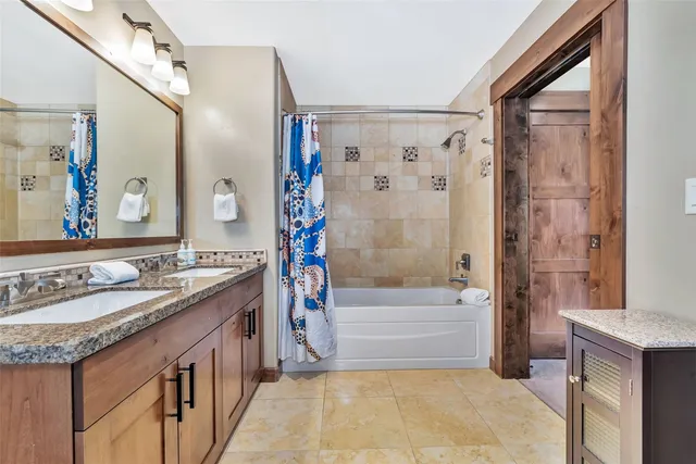 a bathroom with a granite countertop sink a mirror a bathtub and shower