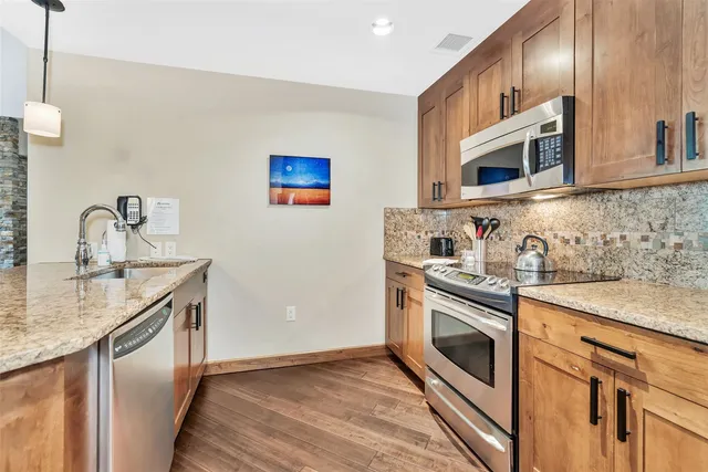 a kitchen with stainless steel appliances granite countertop a sink and a stove top oven