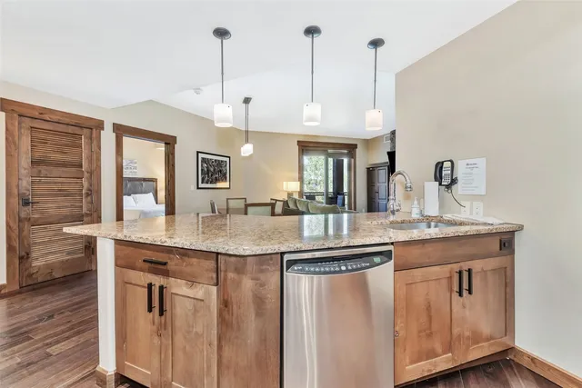 a kitchen with kitchen island granite countertop a sink a counter space appliances and cabinets
