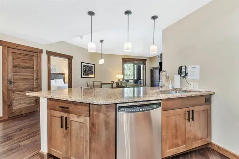 a kitchen with granite countertop a refrigerator stove and microwave with wooden floor