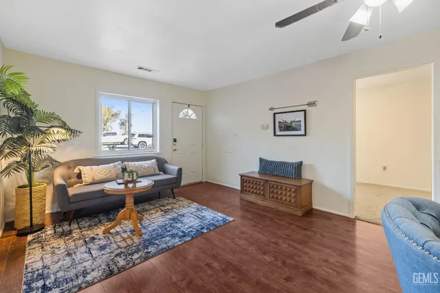 an empty room with wooden floor chandelier fan and windows