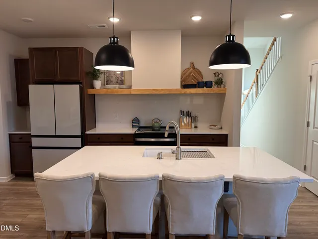 a kitchen with stainless steel appliances a stove a refrigerator a sink a dining table and chairs