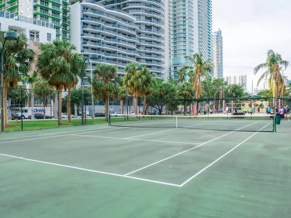 a view of a tennis ground with large trees