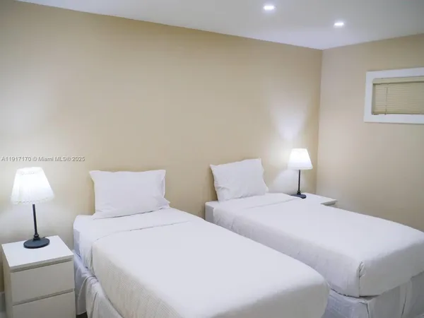 a bedroom with two bed and a lamp