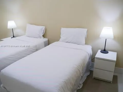 a bedroom with two bed and a lamp